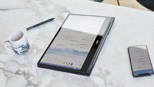 Tablet sitting on a counter next to a mug and a mobile device