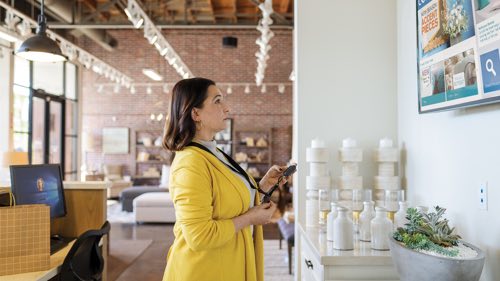 Person standing in a lobby looking at a wall mounted TV screen