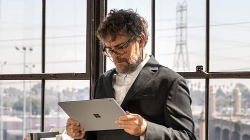Person standing in front of a window looking at a tablet