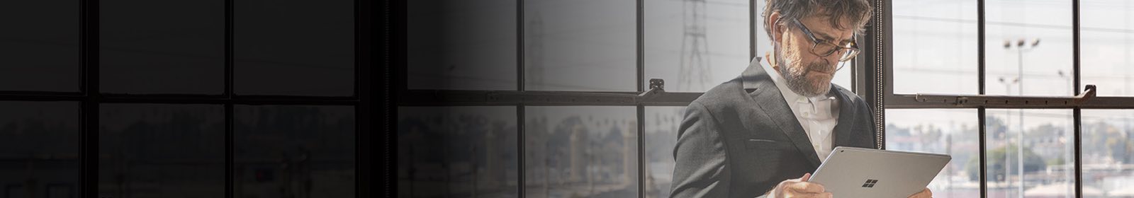 Person standing in front of a window looking at a tablet