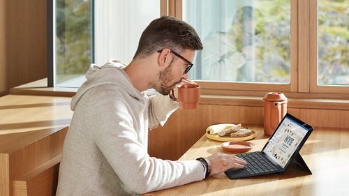 Person in kitchen working on a laptop at a table