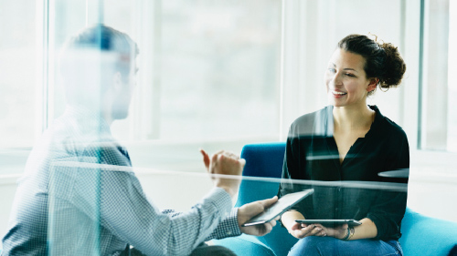 Man and woman discussing on tablets during meeting in office
