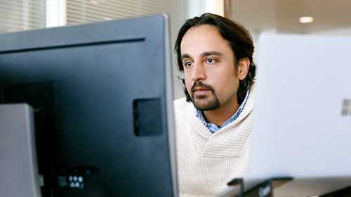 Man working at desk with Surface laptop and monitor