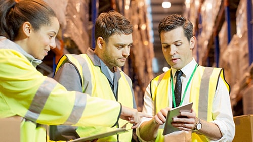 Three people in safety clothing looking at data on tablet