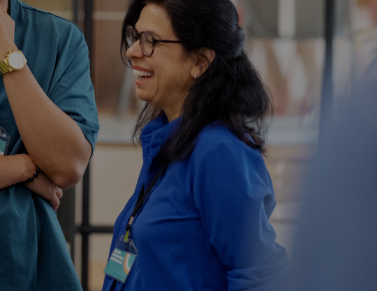 Three coworkers converse and laugh at a business conference.
