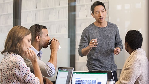 Standing man leading meeting with two men and a woman