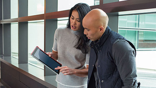 Woman showing man item on her tablet